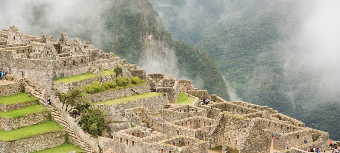 A high angle of the beautiful Machu Picchu citadel surrounded by foggy mountains in Urubamba, Peru